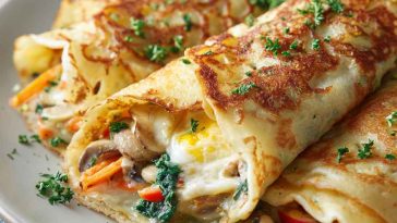Thin golden crepes filled with scrambled eggs, cheese, and fresh herbs, folded and served as a savory breakfast dish.