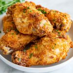 Golden, crispy oven fried chicken served on a platter with parsley garnish.