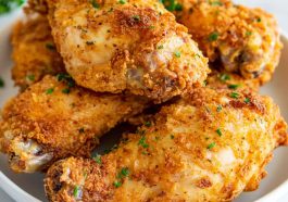 Golden, crispy oven fried chicken served on a platter with parsley garnish.