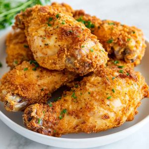 Golden, crispy oven fried chicken served on a platter with parsley garnish.