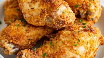 Golden, crispy oven fried chicken served on a platter with parsley garnish.