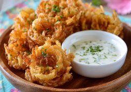 A platter of crispy mini bloomin’ onions served with a side of creamy buttermilk ranch dipping sauce.
