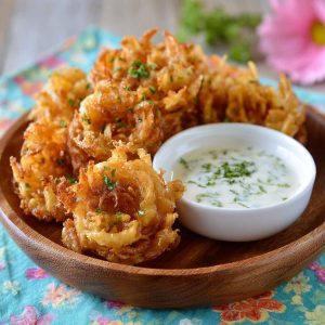 A platter of crispy mini bloomin’ onions served with a side of creamy buttermilk ranch dipping sauce.