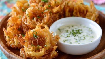 A platter of crispy mini bloomin’ onions served with a side of creamy buttermilk ranch dipping sauce.