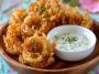 A platter of crispy mini bloomin’ onions served with a side of creamy buttermilk ranch dipping sauce.