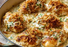 Golden baked sour cream and onion chicken topped with crispy seasoning and fresh herbs, served with a creamy, savory sauce.