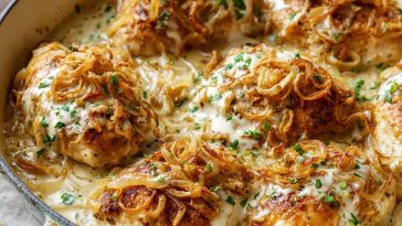 Golden baked sour cream and onion chicken topped with crispy seasoning and fresh herbs, served with a creamy, savory sauce.