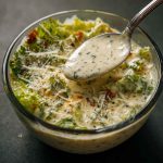 Creamy Italian salad dressing made with herbs, garlic, parmesan, and mayonnaise being drizzled over a fresh garden salad.