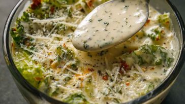 Creamy Italian salad dressing made with herbs, garlic, parmesan, and mayonnaise being drizzled over a fresh garden salad.