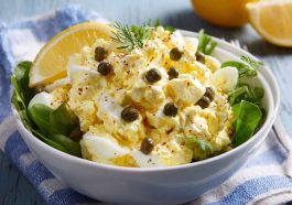 Creamy lemon caper egg salad served in a bowl with fresh herbs and crusty bread slices on the side