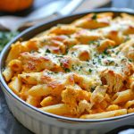 Pumpkin and chicken pasta bake topped with melted cheese in a casserole dish