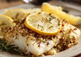Gluten‑free Mediterranean baked cod fillets topped with lemon slices, garlic, and fresh herbs served in a baking dish.