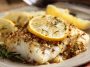 Gluten‑free Mediterranean baked cod fillets topped with lemon slices, garlic, and fresh herbs served in a baking dish.