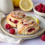 Freshly baked lemon raspberry cream cheese Danish rolls topped with glaze and filled with sweet raspberry and cream cheese filling.