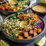 Colorful Thai peanut sweet potato Buddha bowl with roasted sweet potatoes, quinoa, fresh vegetables, and creamy peanut sauce.