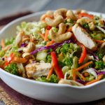 Fresh Chicken Cashew Crunch Salad with crisp lettuce, shredded carrots, crunchy cashews, tender chicken, and a creamy sesame dressing in a bright bowl.