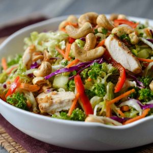 Fresh Chicken Cashew Crunch Salad with crisp lettuce, shredded carrots, crunchy cashews, tender chicken, and a creamy sesame dressing in a bright bowl.