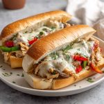"Slow cooker chicken Philly sandwiches with melted provolone, sautéed peppers, and onions on hoagie rolls"