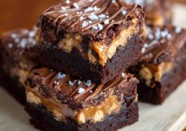 Rich SNICKERS brownies topped with caramel, peanuts, and chocolate chunks on a dessert plate