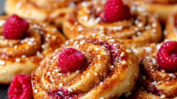 Freshly baked sugar raspberry Danish buns topped with glaze and filled with sweet raspberry jam.