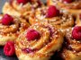 Freshly baked sugar raspberry Danish buns topped with glaze and filled with sweet raspberry jam.