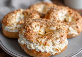 A batch of golden brown cottage cheese protein bagels made with only three ingredients, fresh out of the air fryer, served on a wooden board.