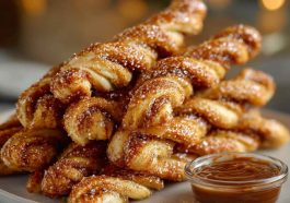 Golden-brown Cinnamon Twists coated with cinnamon sugar, served on a plate with a light glaze drizzle.