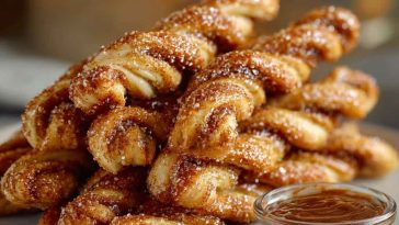 Golden-brown Cinnamon Twists coated with cinnamon sugar, served on a plate with a light glaze drizzle.