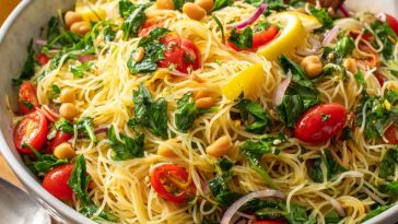 “Capellini pasta tossed with lemon dressing, fresh herbs, and vegetables served in a bowl.”
