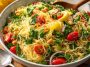 “Capellini pasta tossed with lemon dressing, fresh herbs, and vegetables served in a bowl.”