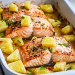 Baked salmon topped with pineapple chunks and glaze in a baking dish