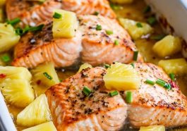 Baked salmon topped with pineapple chunks and glaze in a baking dish