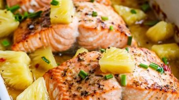 Baked salmon topped with pineapple chunks and glaze in a baking dish