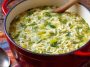 A warm bowl of creamy orzo, leek, and dill soup garnished with fresh herbs, served in a rustic dish.