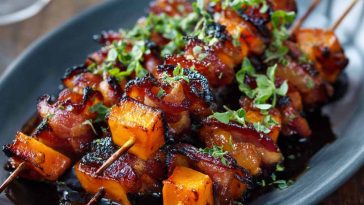 Candied sweet potato and bacon skewers glazed with a sticky brown sugar sauce, roasted until caramelized and crispy, served on wooden skewers.