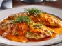 Flaky tilapia fillets in a rich roasted red pepper sauce, garnished with herbs and served in a skillet for a quick and flavorful meal.