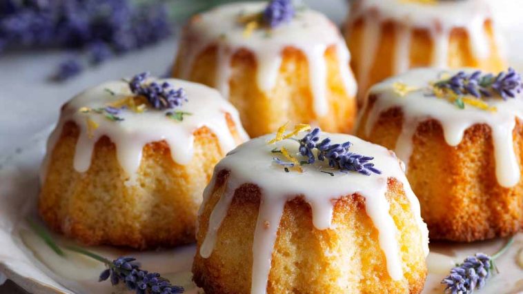 Mini lemon cakes topped with a delicate lavender glaze, soft and moist with a light floral finish, served on a dessert plate.