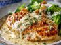 A skillet of creamy Asiago chicken served with a rich garlic cream sauce, garnished with fresh herbs.
