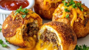 Golden cheesy taco bombs in the air fryer filled with seasoned ground beef and melted cheese, baked in biscuit dough until crispy and served with dipping sauce.
