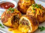 Golden cheesy taco bombs in the air fryer filled with seasoned ground beef and melted cheese, baked in biscuit dough until crispy and served with dipping sauce.