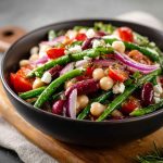 Colorful Mediterranean bean salad with chickpeas, kidney beans, tomatoes, cucumbers, olives, and fresh herbs served in a bowl