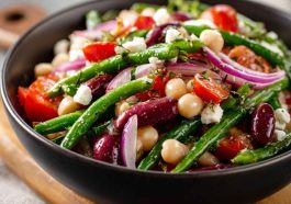 Colorful Mediterranean bean salad with chickpeas, kidney beans, tomatoes, cucumbers, olives, and fresh herbs served in a bowl