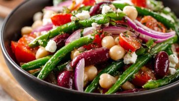 Colorful Mediterranean bean salad with chickpeas, kidney beans, tomatoes, cucumbers, olives, and fresh herbs served in a bowl