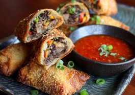 Voodoo Egg Rolls with crispy golden wrappers, filled with savory ingredients, served with spicy dipping sauce.