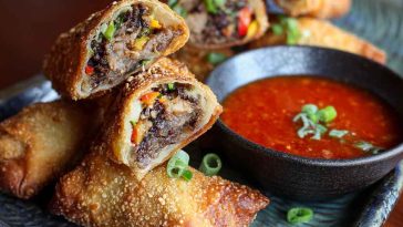 Voodoo Egg Rolls with crispy golden wrappers, filled with savory ingredients, served with spicy dipping sauce.