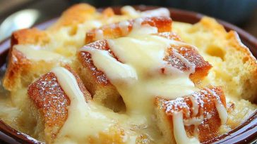 Classic old fashioned bread pudding topped with creamy vanilla sauce, served warm in a rustic dish.