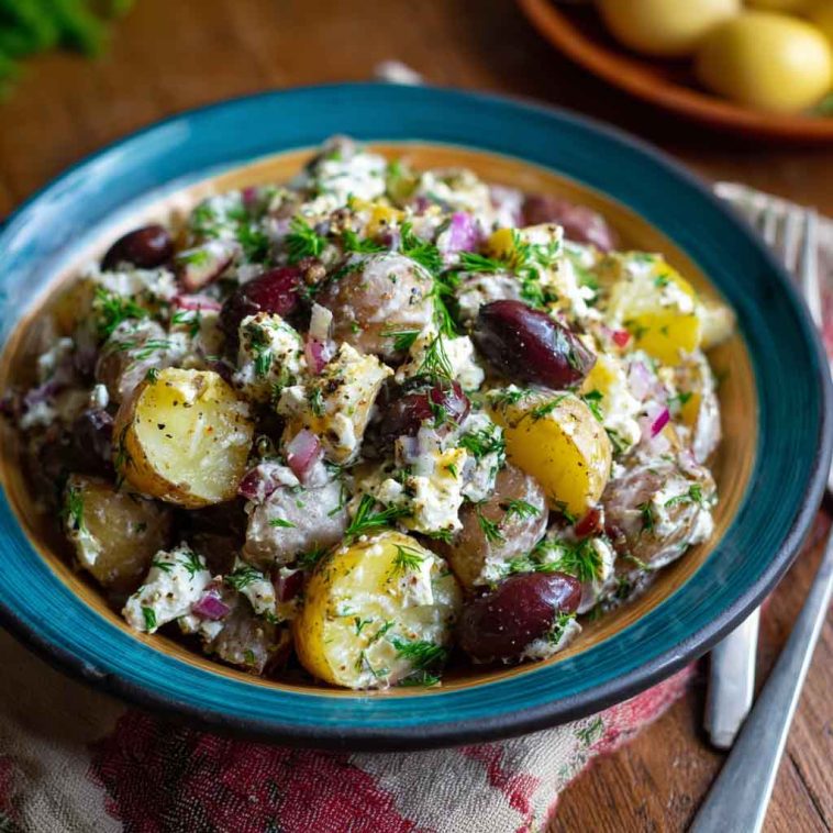 Colorful olive Greek potato salad with red potatoes, Kalamata olives, cucumbers, tomatoes, and feta cheese tossed in lemon‑herb dressing.
