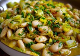 Flavorful butter beans with sautéed leeks served in a rustic bowl, garnished with fresh herbs and olive oil.