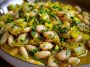 Flavorful butter beans with sautéed leeks served in a rustic bowl, garnished with fresh herbs and olive oil.