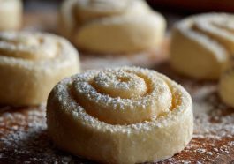 Freshly baked lemon rolls drizzled with sweet glaze, arranged on a plate with lemon slices.